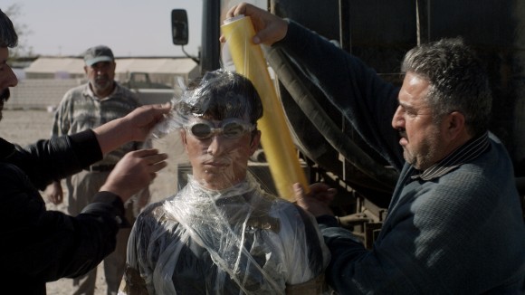 Siyar (Taher Abdullah Taher) wird mit Folie vor Öl geschützt; Standbild aus dem Film 
